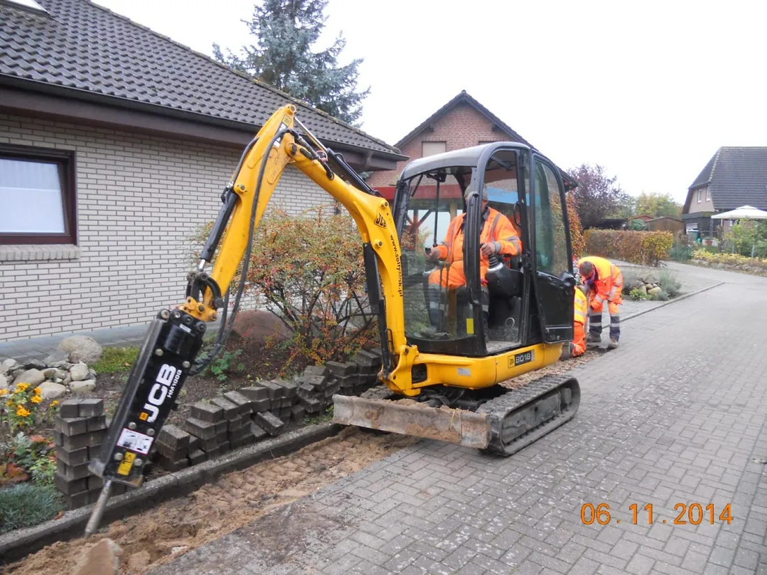 Koparka z młotem hydraulicznym rozbija podbudowę chodnika
