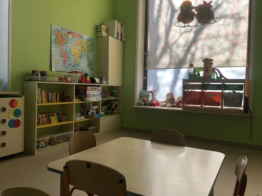 Zielona sala z mapą świata i regałami z zabawkami